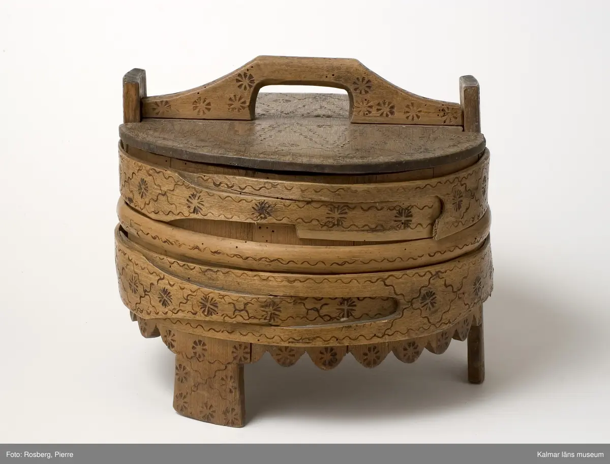 KLM 7013. Grötbytta. Tillverkad av trä, laggad, stavar av furu, botten och lock av ek. Band av björkspån och vidjor. Ornering i form av glödstämplade våglinjer och blommor på sidor och lock.