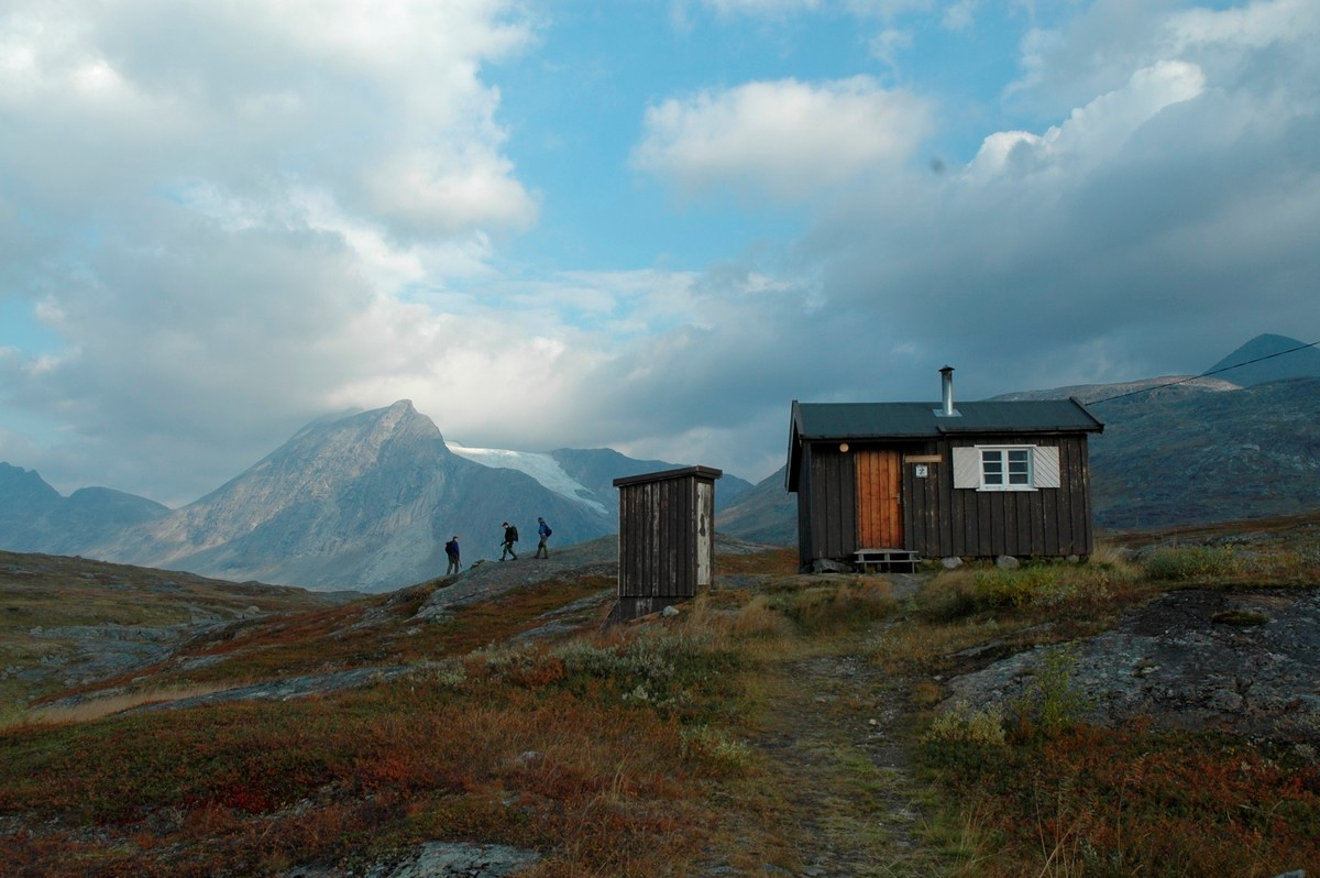 Losi-hytta til turistforening på Skjomfjellet. Tre jegre på tur innover dalen. Lillehytta (sikringshytte) til høyre og utedo.  Foto: Harald Harnang.