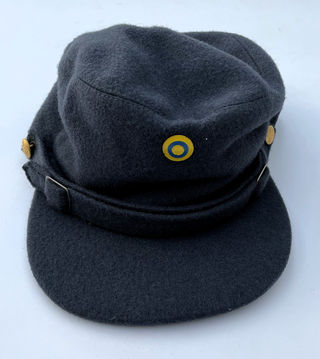 Mörkt blågrå Vintermössa m/1950-1960 i kläde. Modell som vintermössa m/1950. Nationalitetsmärke m/1941 och små knappar m/1939-1960 i guld.