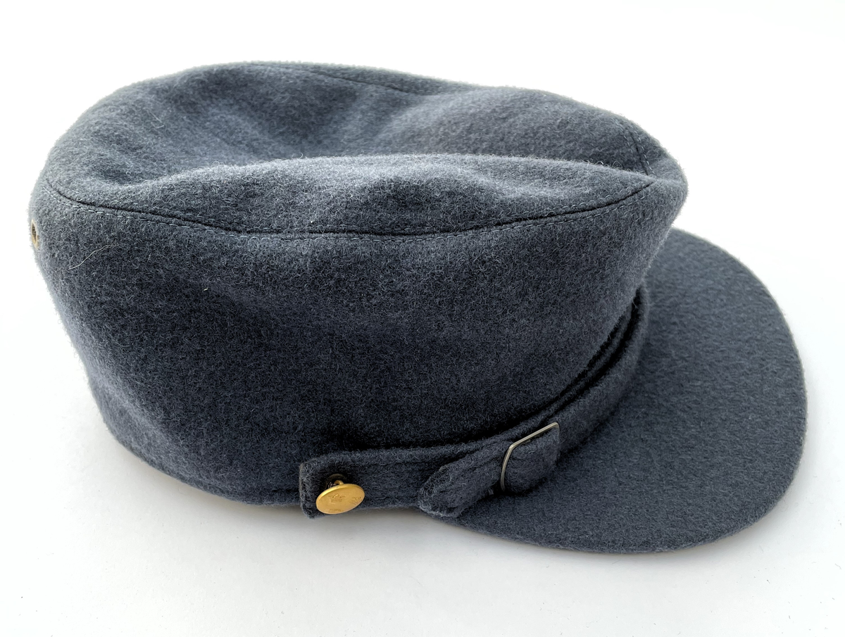 Mörkt blågrå Vintermössa m/1950-1960 i kläde. Modell som vintermössa m/1950. Nationalitetsmärke m/1941 och små knappar m/1939-1960 i guld.