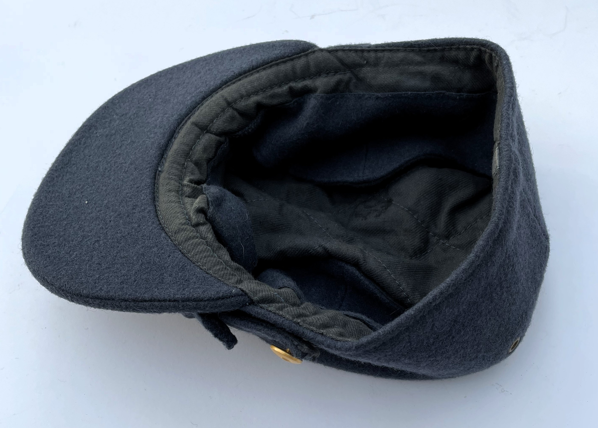 Mörkt blågrå Vintermössa m/1950-1960 i kläde. Modell som vintermössa m/1950. Nationalitetsmärke m/1941 och små knappar m/1939-1960 i guld.