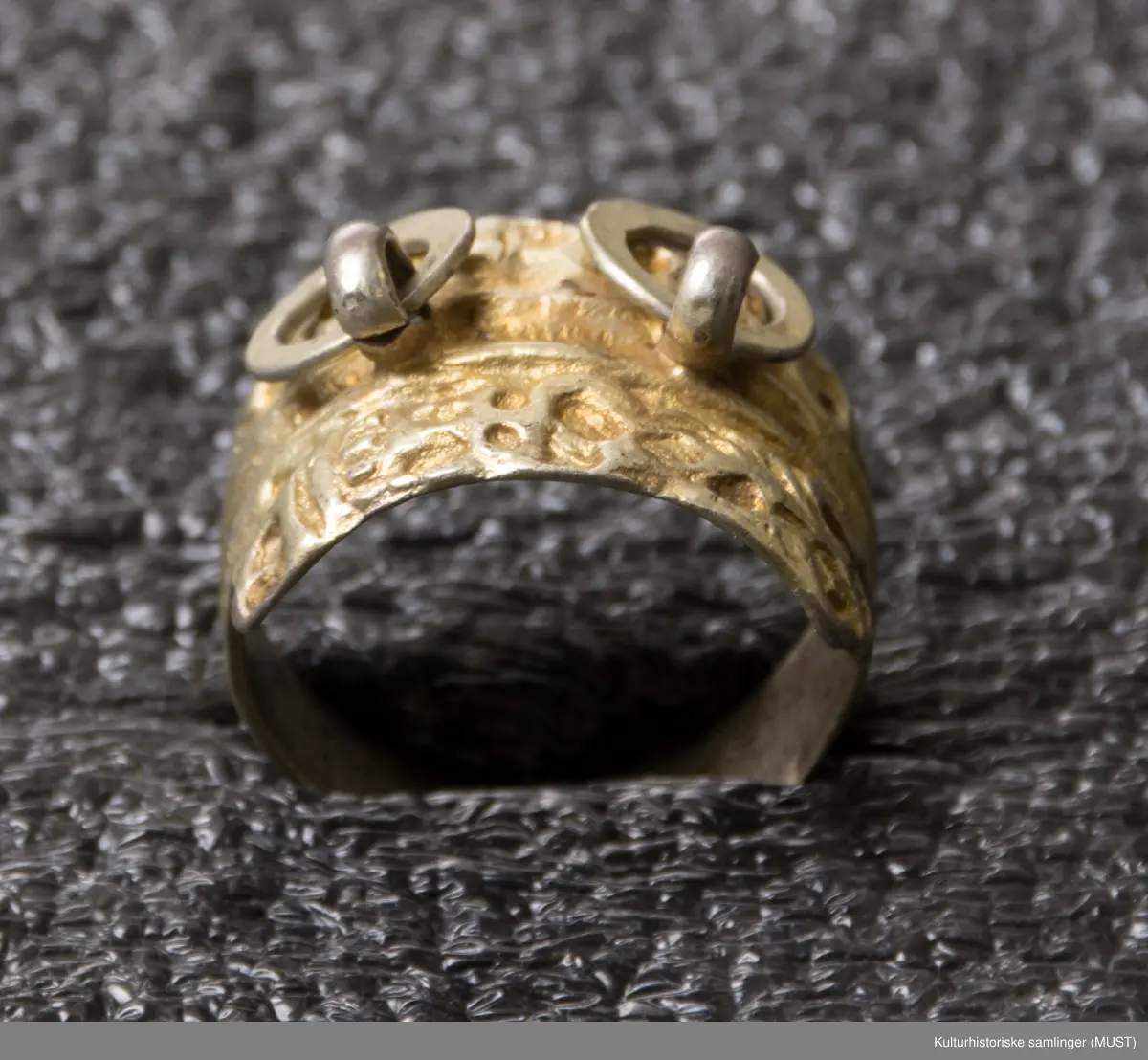 Ring som utvider seg til en plate med to ringer i front.