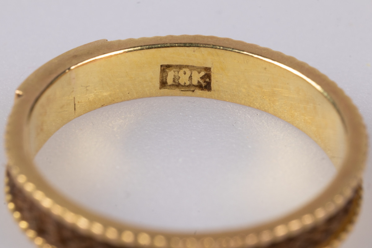 18 karats gullring med flettet hår rundt yttersiden av ringen. På innsiden er der et legeringsstempel og inngravert monogram