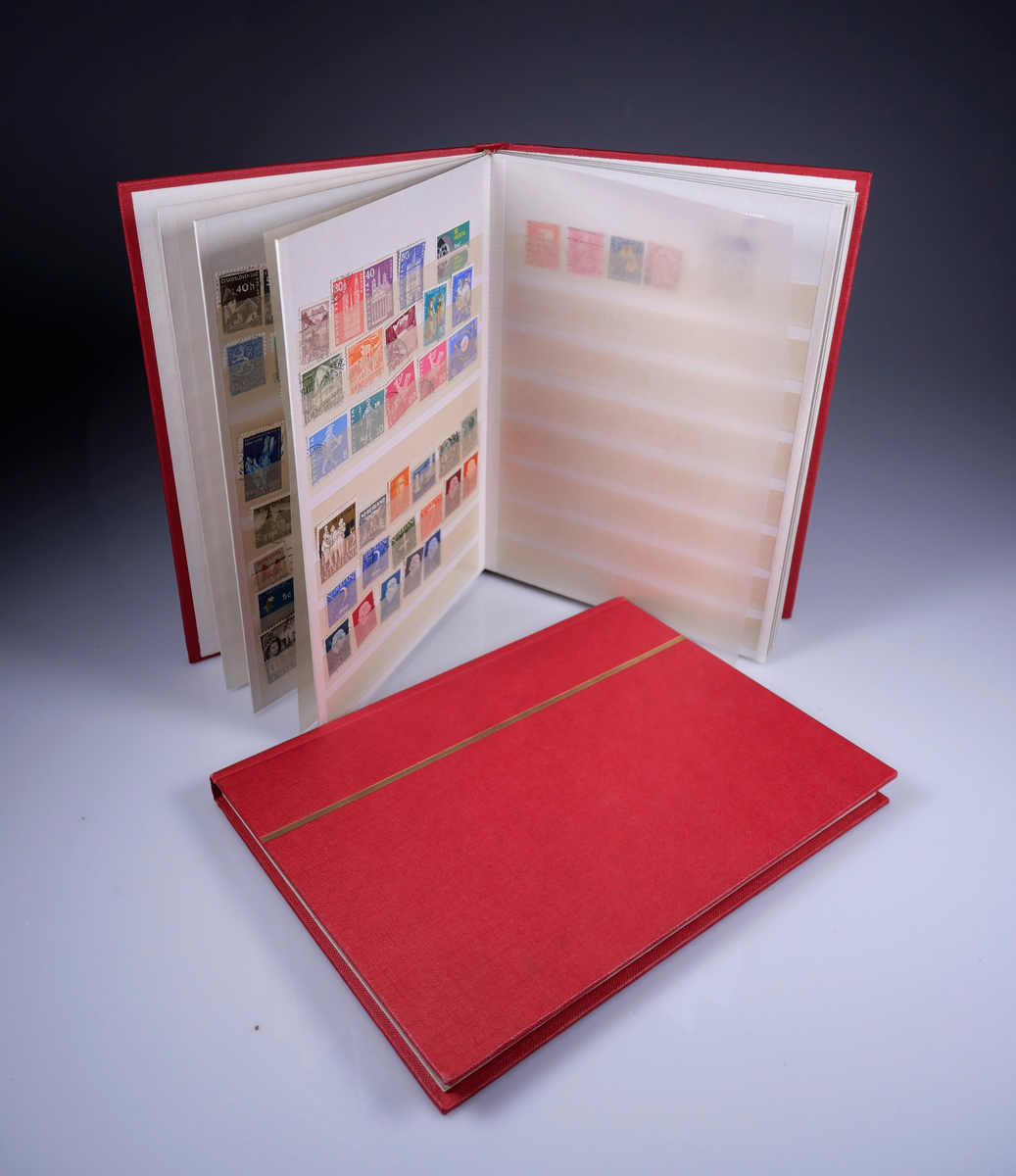 2 röda frimärksalbum tillhörande frimärkssamling som givaren hade som barn på 1960-talet. Frimärken samlades dels från föräldrarnas post men också från färdigköpta lådor med frimärken (AM 2024-006-3).