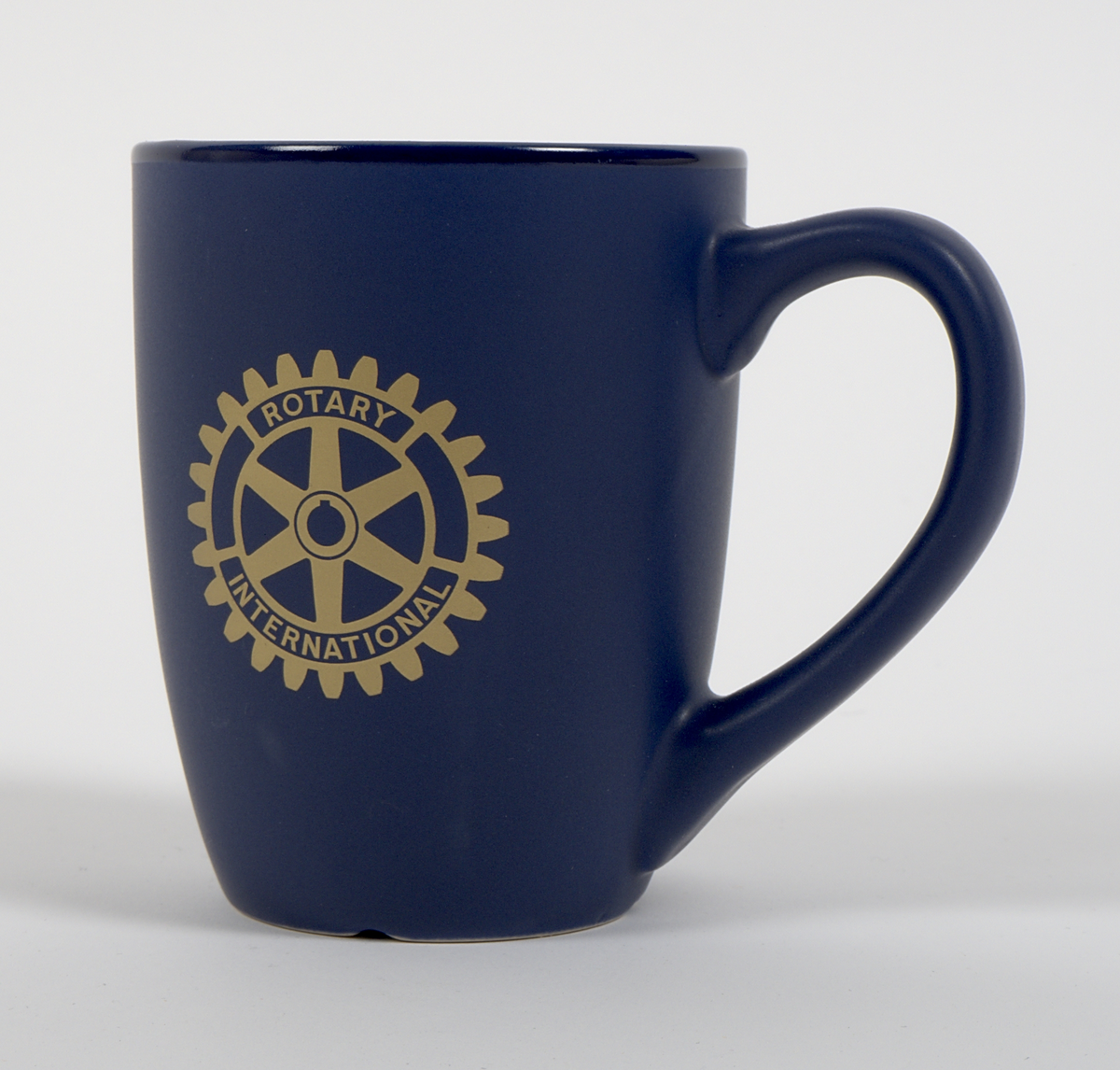 Kaffemugg av blåglaserat stengods. Rak, cylindrisk form, med öra. Två grafiska tryck i guldfärg på vardera sida av muggen. På ena sidan: Rotary international-logotyp. På motsatt sida: Vy över Varbergs fästning med Bockstensmannen i förgrunden, samt texten "Jag blev utvald att tala hos Varberg-Bocksten Rotaryklubb."