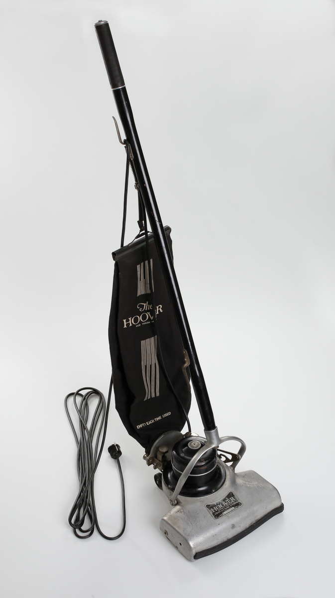 Elektrisk dammsugare av märket The Hoover, tillverkad i USA mellan åren 1923-25. Dammsugaren består av ett sugmunstycke på fyra mindre hjul och med roterande borste. Motorn är placerad ovanpå munstycket. Från sugmunstycket leder ett fällbart/ledat skaft samt en monterad textil dammsugarpåse som går att lossa och haka av vid tömning.