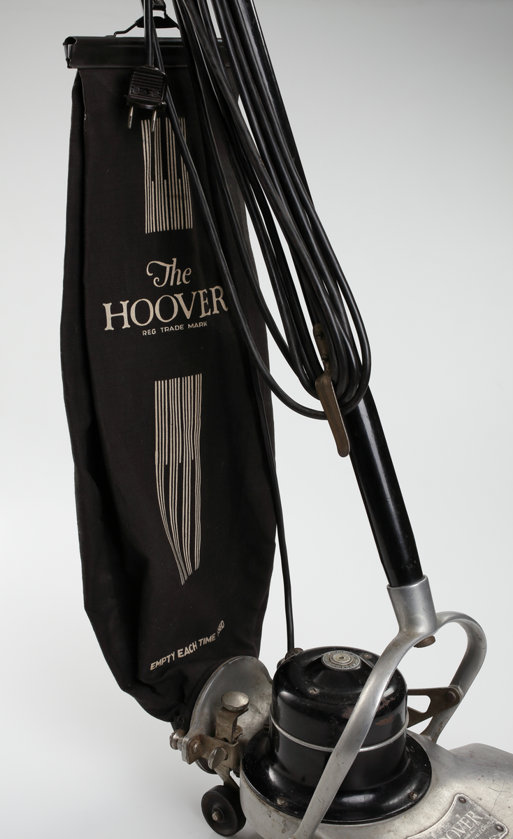 Elektrisk dammsugare av märket The Hoover, tillverkad i USA mellan åren 1923-25. Dammsugaren består av ett sugmunstycke på fyra mindre hjul och med roterande borste. Motorn är placerad ovanpå munstycket. Från sugmunstycket leder ett fällbart/ledat skaft samt en monterad textil dammsugarpåse som går att lossa och haka av vid tömning.