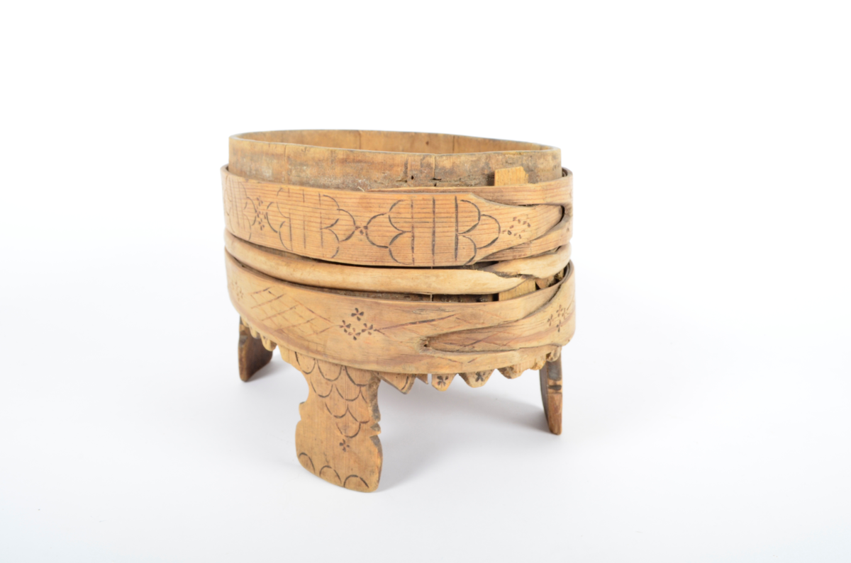 Trekar i furu og bjørk. Lagget, oval form, fire høye ben. To brede gjorder med en vidje i mellom. Sviornamentikk på gjorder og ben.