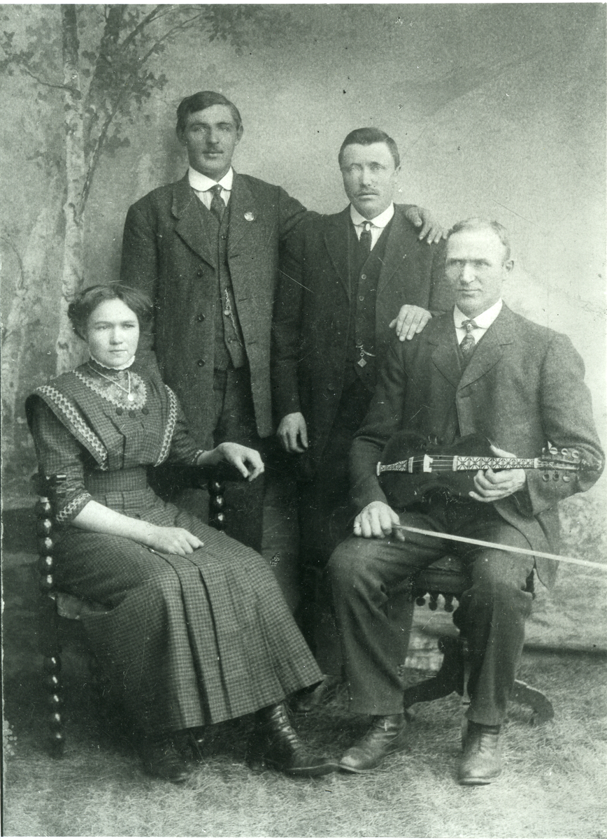 Gruppebilde
Familien Grimsgård. Sittende fra v, Oline, f. Grimsgård, gift Mjølid, broren Helge Grimsgård med fele. Bakerst f.v. Andreas Grimsgård og ukjent
