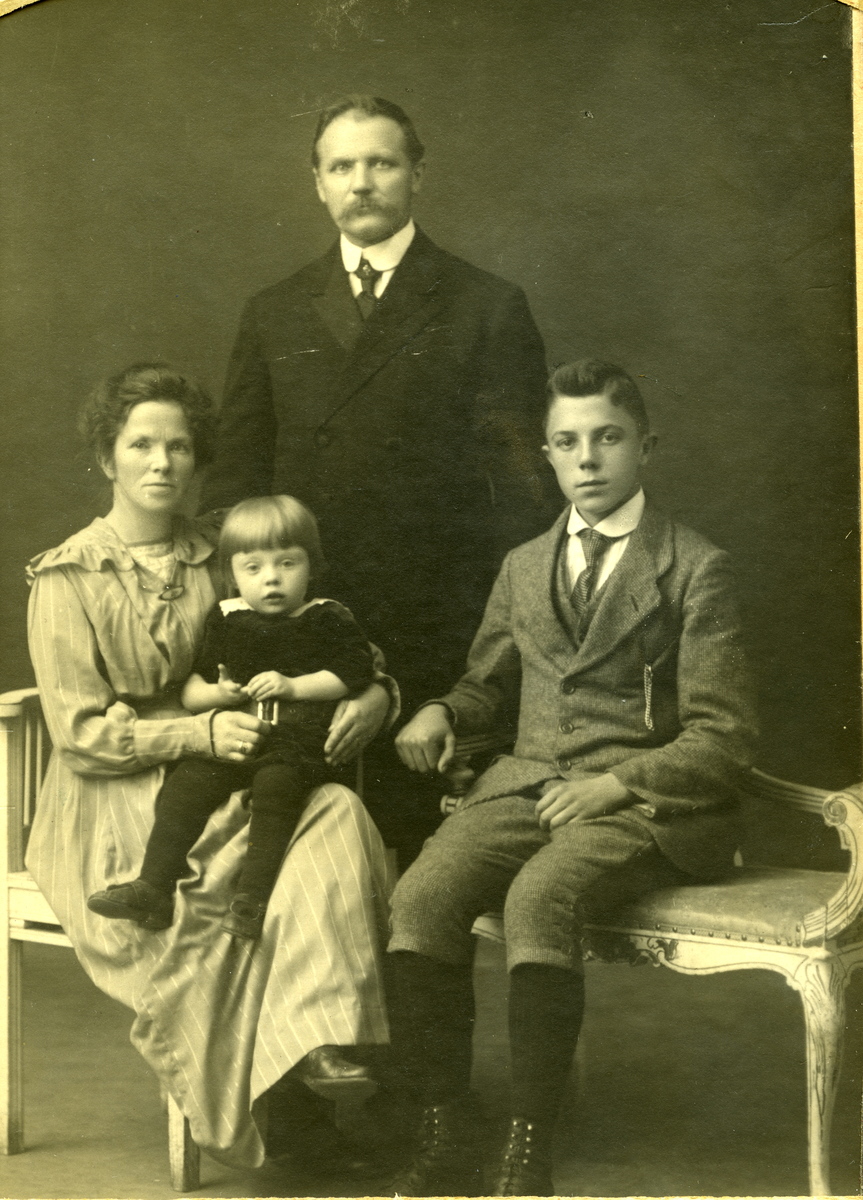 Familiegruppe
Familien Ole Tyribakken d.e., f. 1876, og Anna f. Hagen med sønnene Erik Tyribakken t.v. og Thor Tyribakken. Ole var en eldre bror av Truls Tyribakken. Han var i mange år brødkjører og senere kjøpmann i Asker. Kona Anna var fra Asker.
