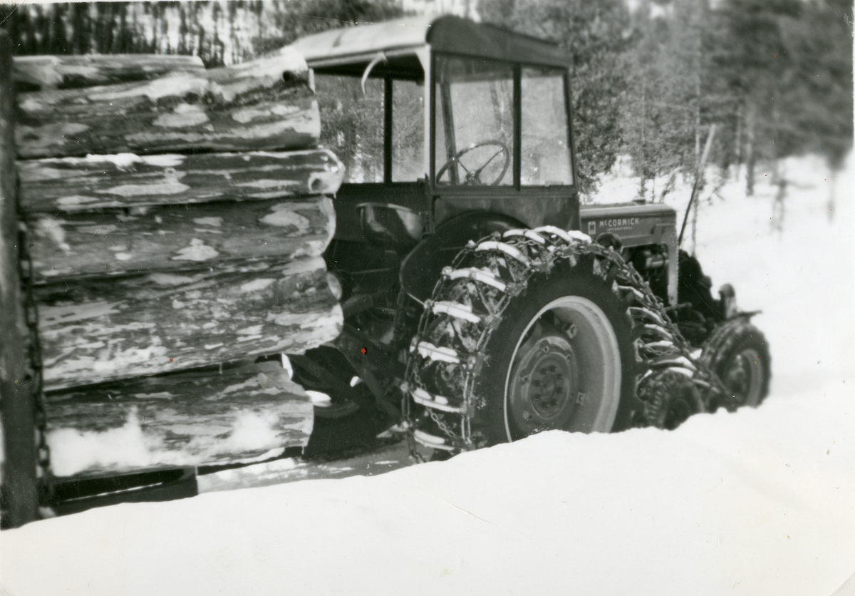 Tømmerkjøring fra Garnåsskogene med traktor, International McCormick. Traktoren er utstyrt med halvbelter. Eier var Oskar Hallibakken.

