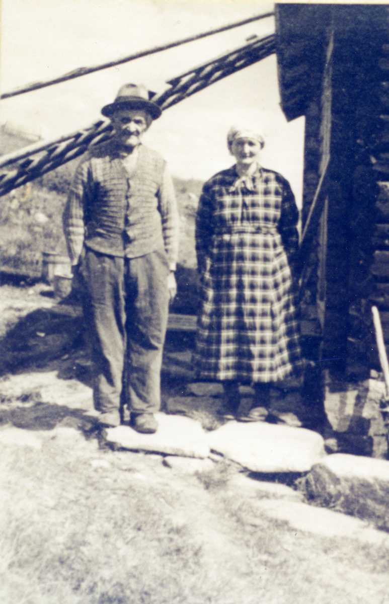 Ektepar i hverdagsklær ved gårdsbygning. Fra N. Gudbrandsrud. Ola og Mette Gudbrandsrud, f. Sletten.
