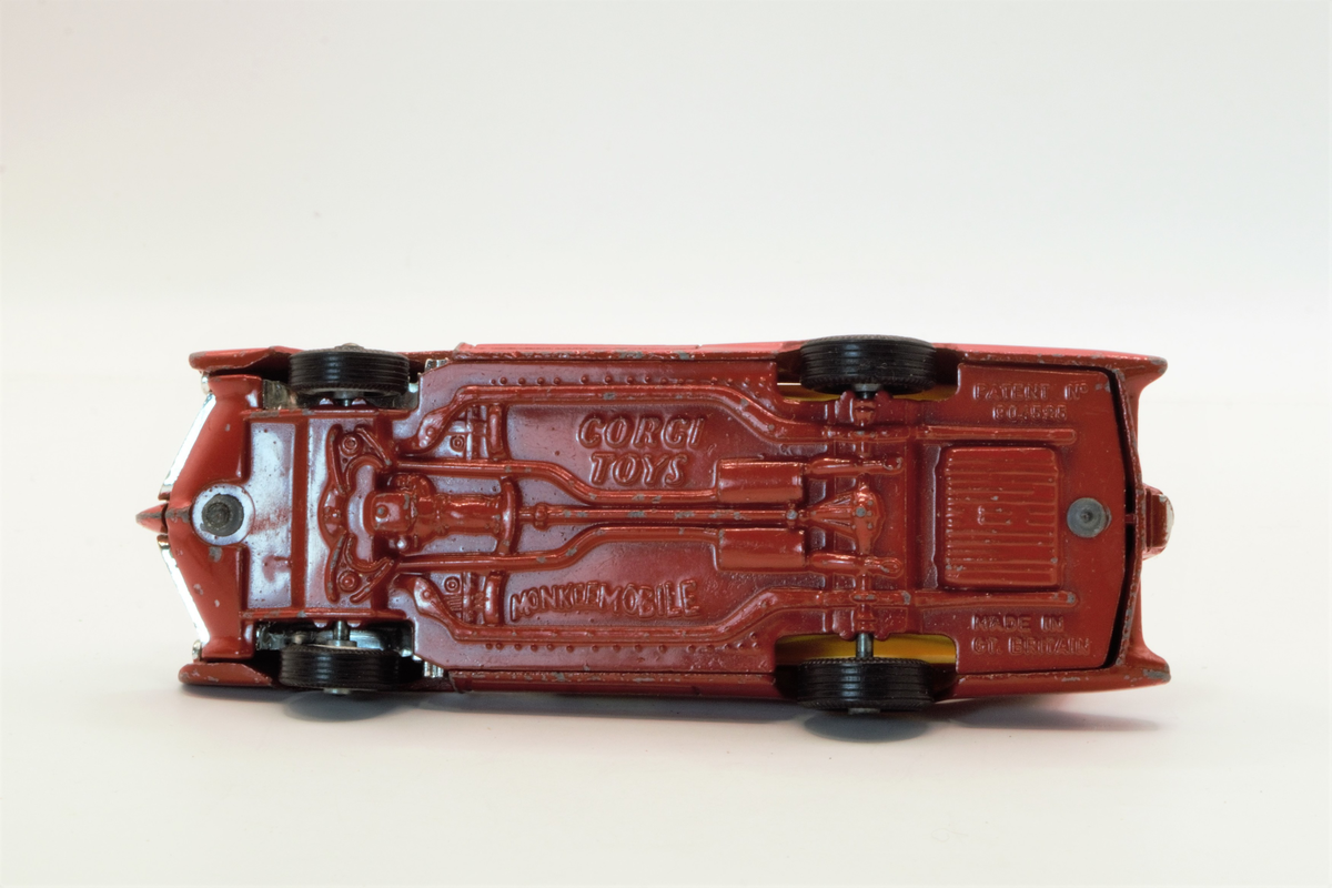 Rød lekebil fra 60/70-tallet. Produsert i Wales. The Monkeemobil. Modell av Dean Jeffries 1966 Pontiac GTO som var med i den amerikanske TV-serien The Monkees. Fire figurer i setene som spiller gitar og vinker, karakterene i serien spiller i band.