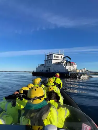 Her ser vi RIb båten med folk ombord ankomme havbruksanlegg
