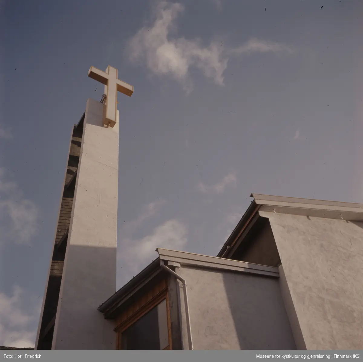 Klokketårnet til den nye katolske kirke St. Mikael i Hammerfest har reist seg og toppes av et stort, lyssatt kors. Himmelen er lett skyet.