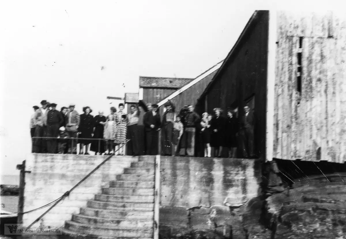 Bildet er tatt 22.09.1946, da tvillingene Kjellaug og Liv Nesje kommer tilbake fra konfirmasjonen. Tvillingene var døtrene til Judith, som var datter til Sivert Julshavn (handelsmann på Søre)..(Kilde: Ivar Hallsteinsens bok 6 om Bjørnsund, side 1480)