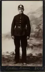 Studioportrett av ung mann i uniform. Helfigur.