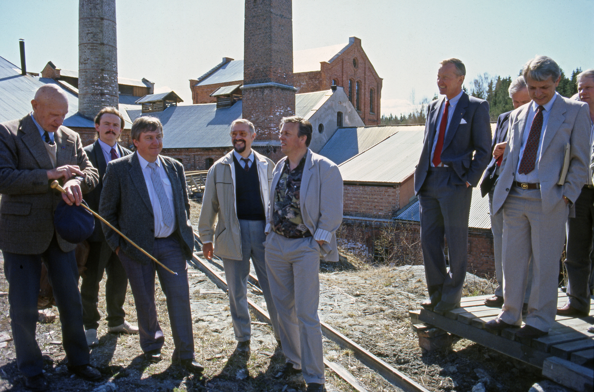 Den 7. mai  ble det avviklet ei samling som representanter for Klevfos industrimuseums venner seinere kalte «Stormøtet på Klevfos», som var et forsøk på å samle representanter for de miljøene museet skulle presentere historia til, i håp om å kunne mobilisere støtte til å få reist et museumsbygg på Ådalsbruk. Mange sentrale tillitsmenn, byråkrater og politikere deltok, blant annet lederne i Landsorganisasjonen og Næringslivets Hovedorganisasjon, Yngve Hågensen og Karl Glad. Erik Mollatt representerte treforedlingsindustrien (TFL) og forbundsstyret i Fellesforbundet var på plass sammen med den politiske ledelsen i Hedmark fylkeskommune. Kultursjefen i Løten, Amund Trætteberg, var leder i venneforeningen og hovedvert for arrangementet. Han ble assistert av veteranter fra fabrikkmiljøet, som var omvisere for de viktige gjestene på det som en gang hadde vært deres arbeidsplass. Til venstre på dette fotografiet ser vi Sigurd Tomter (med stokk), som var en av omviserne. Ved sida av ham, som nummer tre fra venstre, ser vi Jens Petter Jensen, som i mange år var Fellesforbundets representant i Klevfos-styret og fusjonen med Norsk Skogbruksmuseum også i det nye Norsk skogmuseums styre. Til høyre for ham (i lys fritidsjakke) ser vi en smilende Yngve Hågensen. Karl Glad står fremst på plattingen i den høyre delen av bildet. Fotografiet er tatt fra en posisjon nord for det største bygningskomplekset på fabrikken. Den pengeinnsamlinga dette møtet skulle være en slags introduksjon til kom, tross bidrag fra fagbevegelsen, aldri i mål. 1991 ble likevel et viktig år i kulturminnet Klevfos' historie for i desember dette året ble Stiftelsen Klevfos etablert som en organisatorisk overbygning for det som etter hvert skulle bli et viktig industrimuseum.