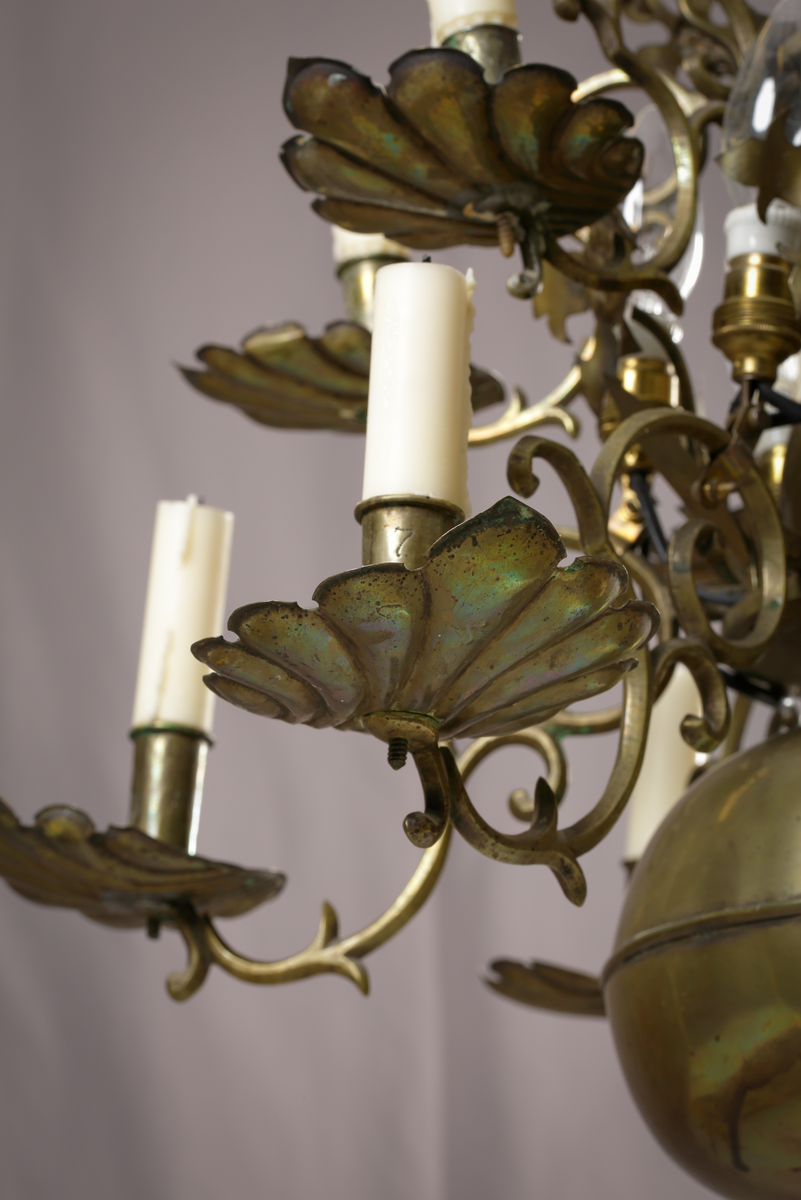 En ljuskrona av mässing, tolvarmad och försedd med anbringbara ornamenter. Kronan har profilerad mittstång, ändklot och tolv s-formade ljusarmar med cylindriska pipor och musselformade droppskålar. Reflexornamenten är blomformade. Ljuskronan är försedd med elektrisk belysning.

Inskrivet i huvudboken 1907.