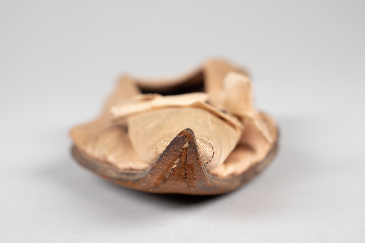 Rosa, håndsydd damesko eller tøffel i silke med spiss tå og flat lærsåle uten hæl. Dekorert med rosett med paljetter på rista.