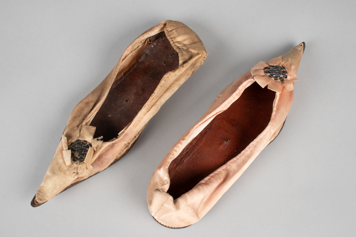 Rosa, håndsydd damesko eller tøffel i silke med spiss tå og flat lærsåle uten hæl. Dekorert med rosett med paljetter på rista.