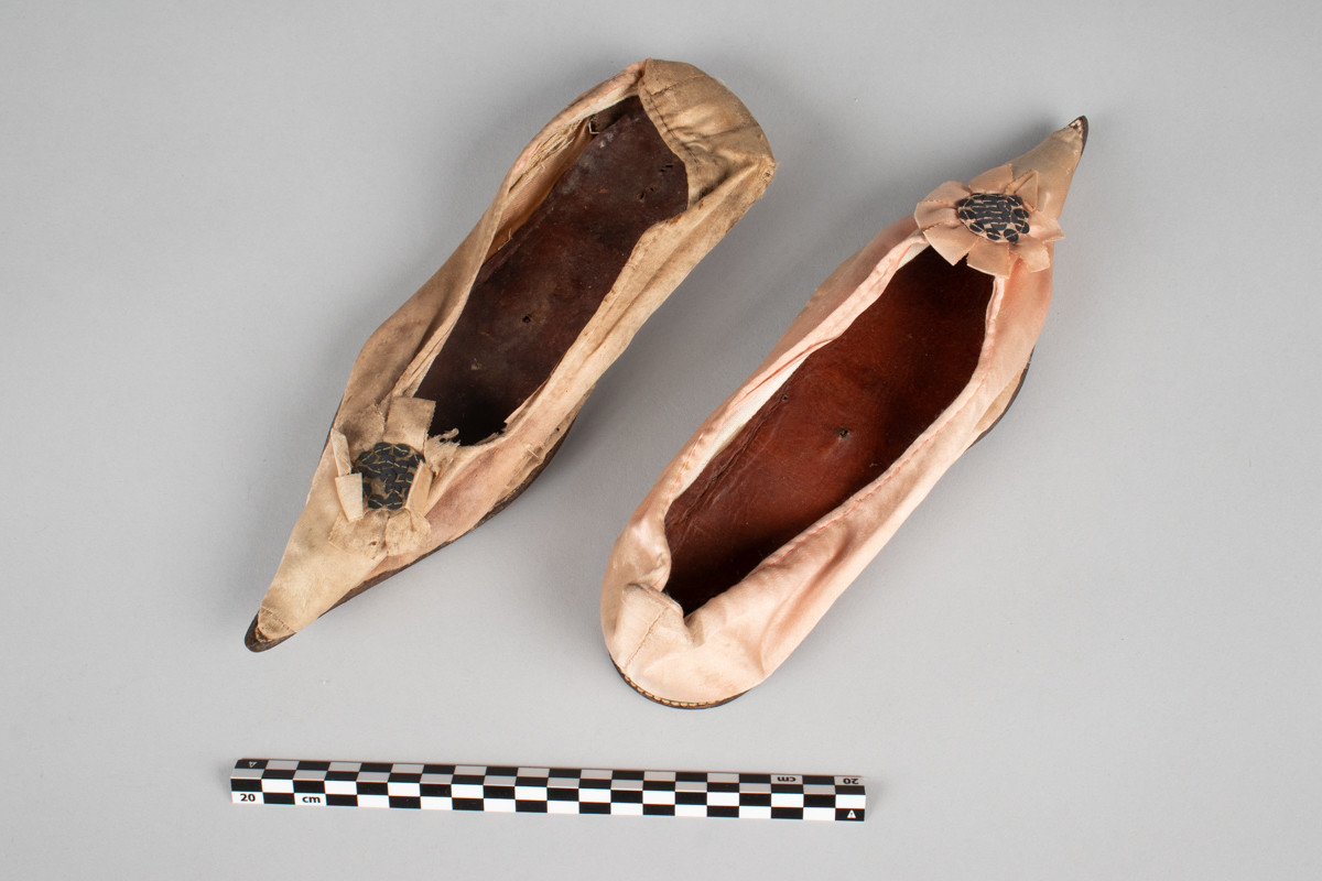 Rosa, håndsydd damesko eller tøffel i silke med spiss tå og flat lærsåle uten hæl. Dekorert med rosett med paljetter på rista.