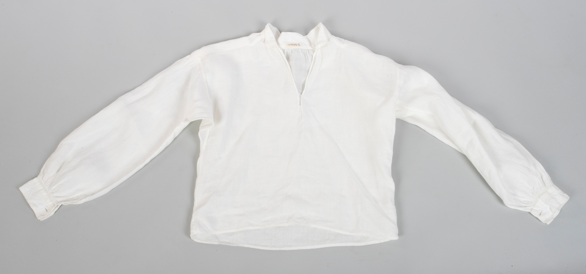 Linskjorte tilhørende kvinnedrakten fra Hitra. 
Broderinger på kragen og mansjettene. 
Kvaderatisk snitt
