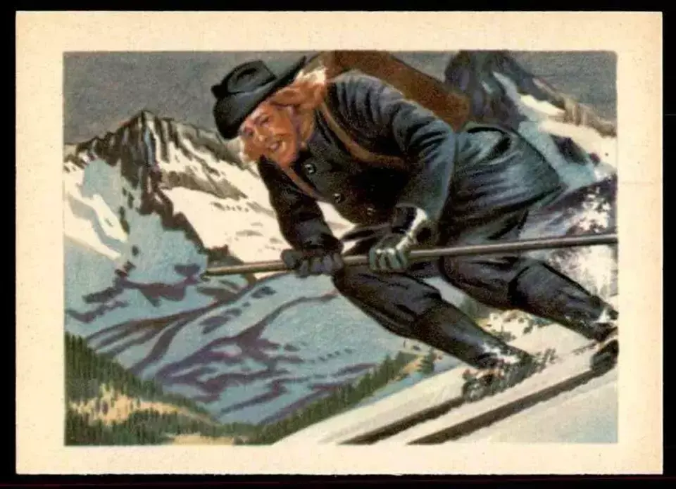 Trykk, bilde på ski ned bratt fjellside med mørke klær, hatt og sekk på ryggen. Smilende mann med skjegg og langt, lyst hår, med bøyde knær og en stav i hånden