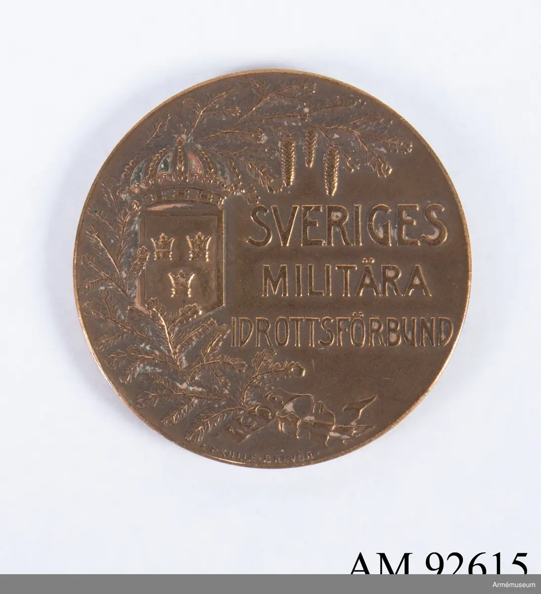 Medalj i brons för Sveriges militära idrottsförbund.
I relief på framsidan syns en grankvist, riksvapnet och texten Sveriges Militära Idrottsförbund, samt årtalet 1909 i ett språkband nertill. I liten stil står gravörens namn S. Kulle.
På frånsidan syns idrottens beskyddarinna med lagerkvist i vänstra handen och en sköld med riksvapnet i högra handen. Frånsidan saknar text förutom konstnärens namn V. Carlberg D. i liten stil nertill längs med kanten.