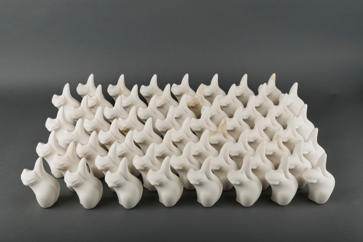 60 små katteskulpturer laget ved Egersunds Fayancefabrik. Skulpturene er udekorerte og uglaserte, og dermed ikke ferdigstilte produkter for salg.