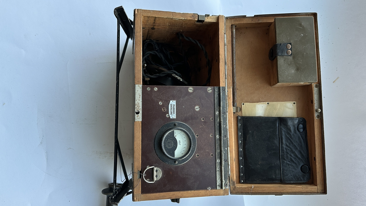 Tysk feltapparat med sveiv. Voltmeter. Skuff med ekstra pærer. Trolig mulighet for å lade et batteri.