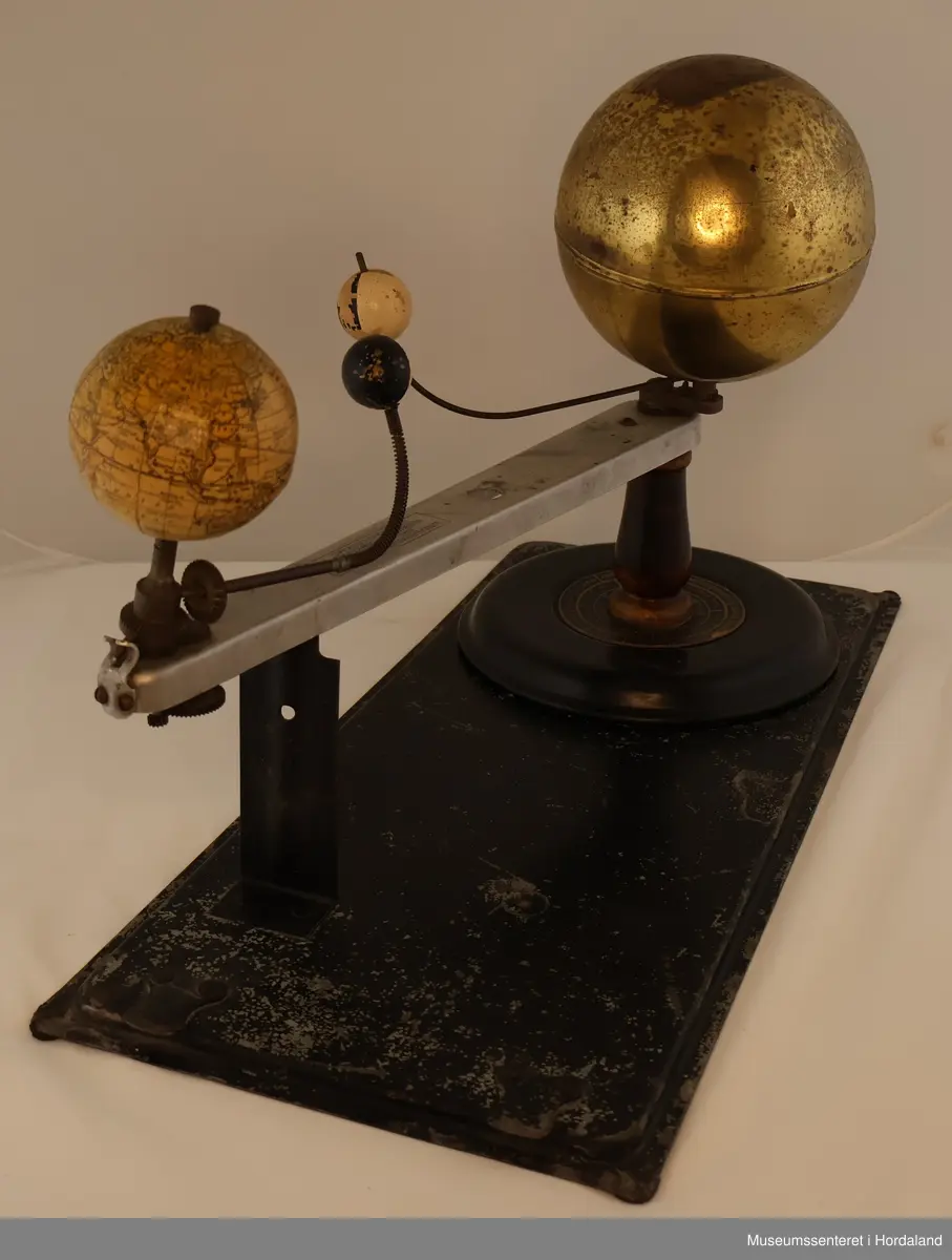 Tellurium av metall med kasse av tre. Telluriet er en modell som består av Sola og Jorda på et stativ med hver sin sfære. På stativet under Sola er en disk med årstider, stjernetegn og månedene påskrevet.
