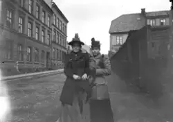 To ukjente kvinner, klær, hodeplagg, bygate, ukjent sted.