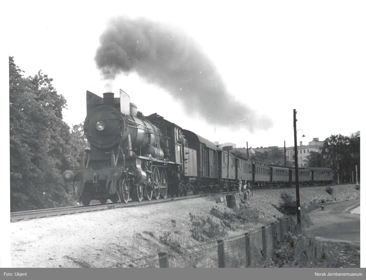 Damplokomotiv type 30a med persontog kjører ut fra Hamar stasjon