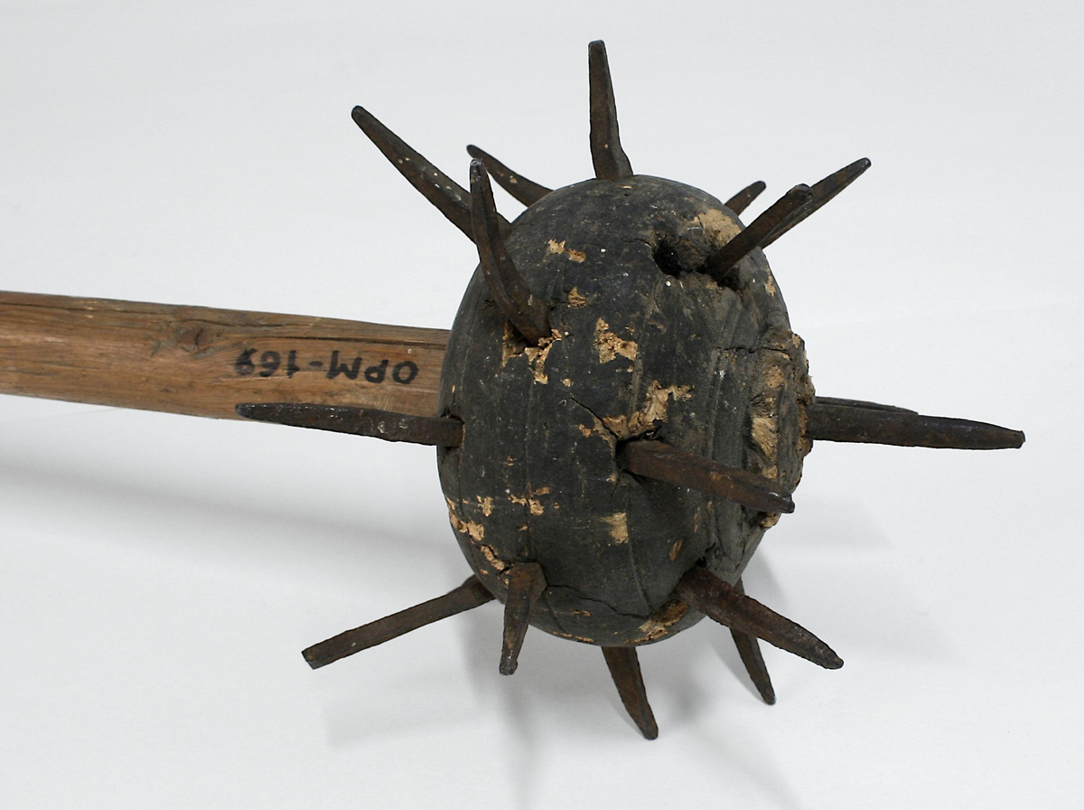 Trestav med en piggete blykule øverst. Kulen har 19 pigger. Staven har en doppsko av jern nederst, formet som en holk med en jernpigg.