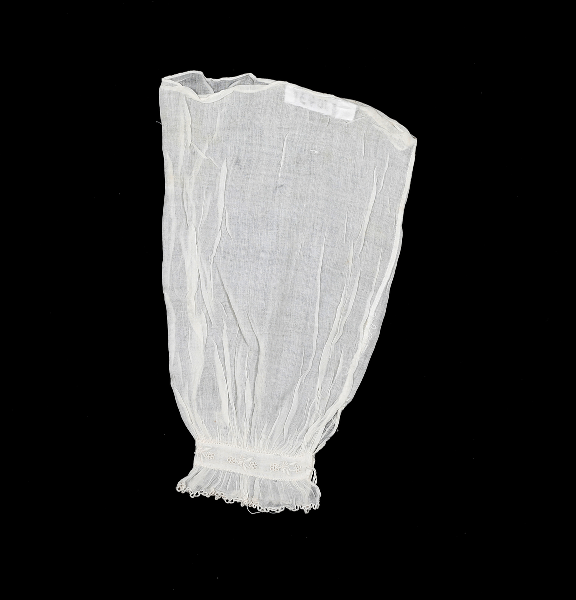 Løserme i tynt stoff. Rynket over og under mansjettlinning. Mansjettlinningen er brodert. Lukkes med hempe og en liten knapp. Sidesømmen i ermet er indresøm. Lappet noen steder. 