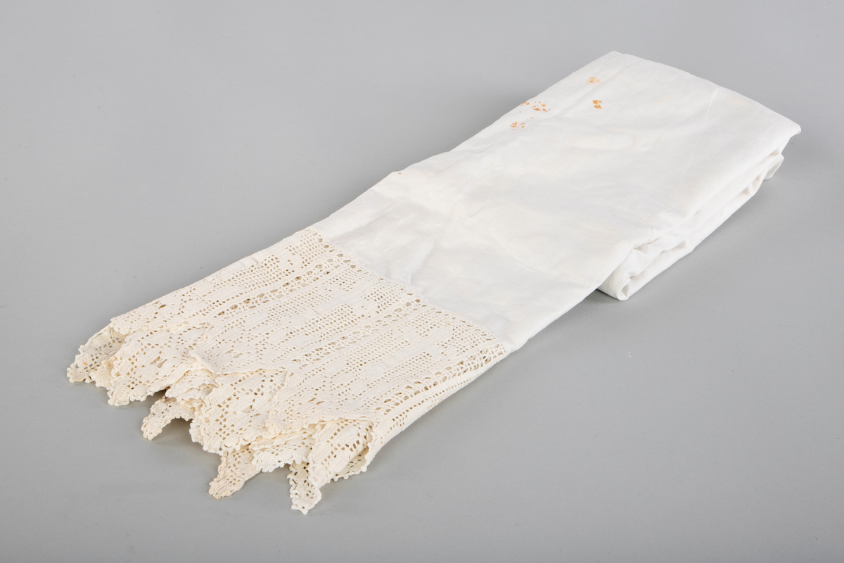 Alterduk i kvit bommullsstoff med hekla bord nederst. Borden er hekla med tynt garn og formen er kors med blomsterdekor under som ender i en spiss. I alt er det 23 kors med blomsterspisser under. 
Formen på duken er kvaderatisk, men med et smalere stykke fra halvparten av duken og oppover.