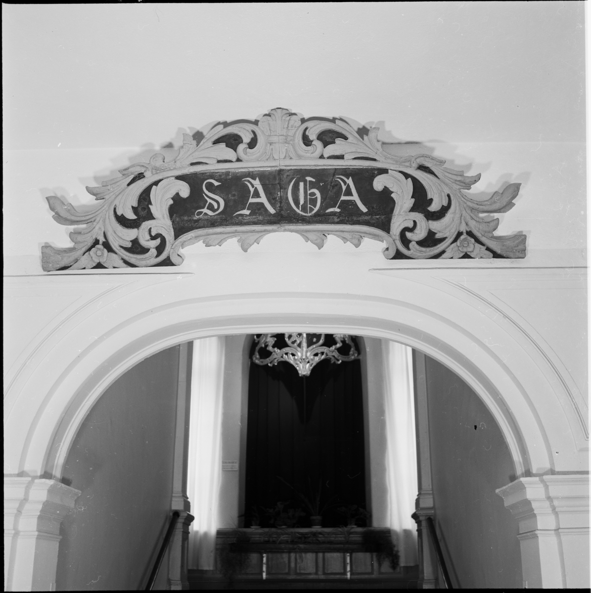 Akterstävsornament från ångkorvetten Saga (byggd vid Karlskrona örlogsvarv år 1878).

Av furuträ och utgöred av namnet Saga, omgivet av blad och blomrankor. Bottenfärg är svart, ornament och namn gula.