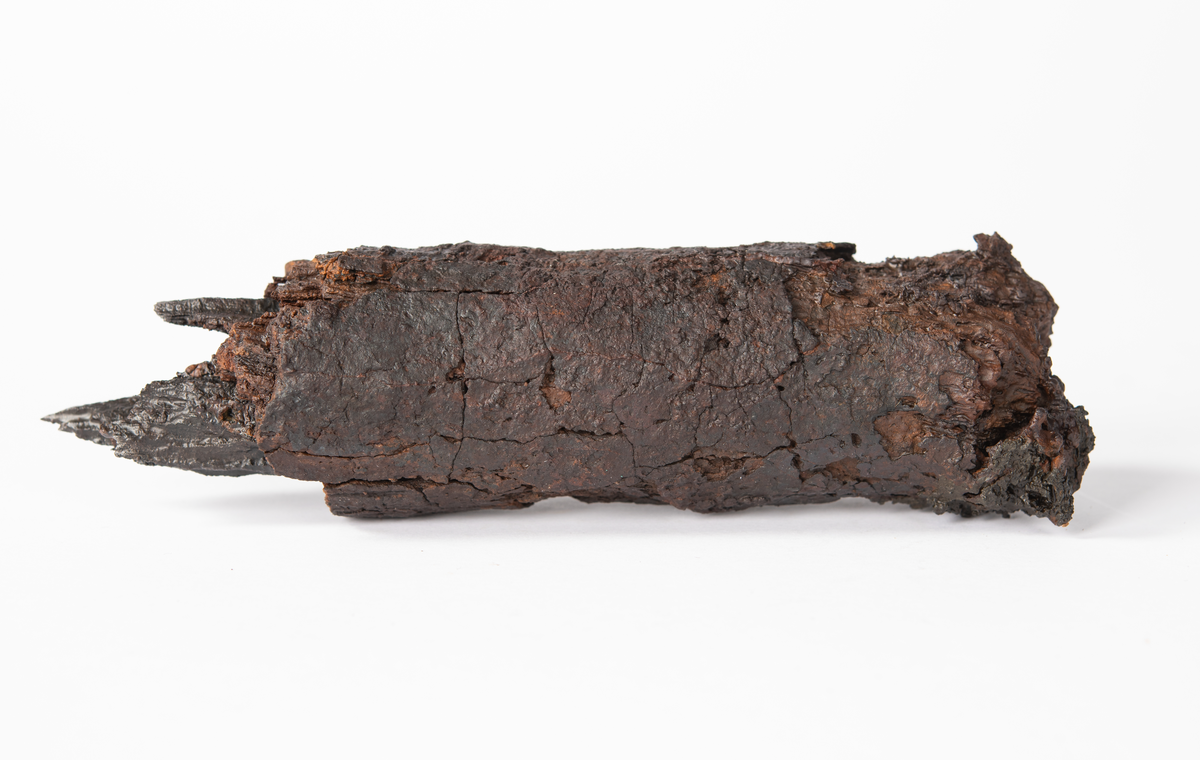 Del av bult. Oklart om det är huvuddelen eller om det är brott i 
bägge ändar. Originalytan är sprucken och mindre delar har fallit av. En större krusta i ena änden.