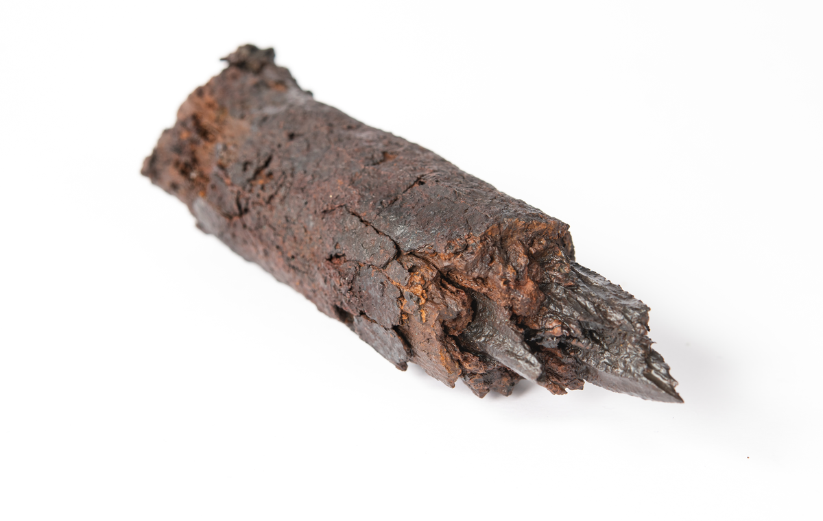 Del av bult. Oklart om det är huvuddelen eller om det är brott i 
bägge ändar. Originalytan är sprucken och mindre delar har fallit av. En större krusta i ena änden.