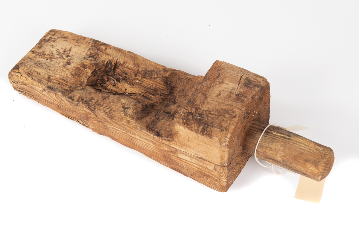 En kil med ett runt handtag som mäter 45 mm i diameter och är 105 mm långt. Ser ut som en kil.