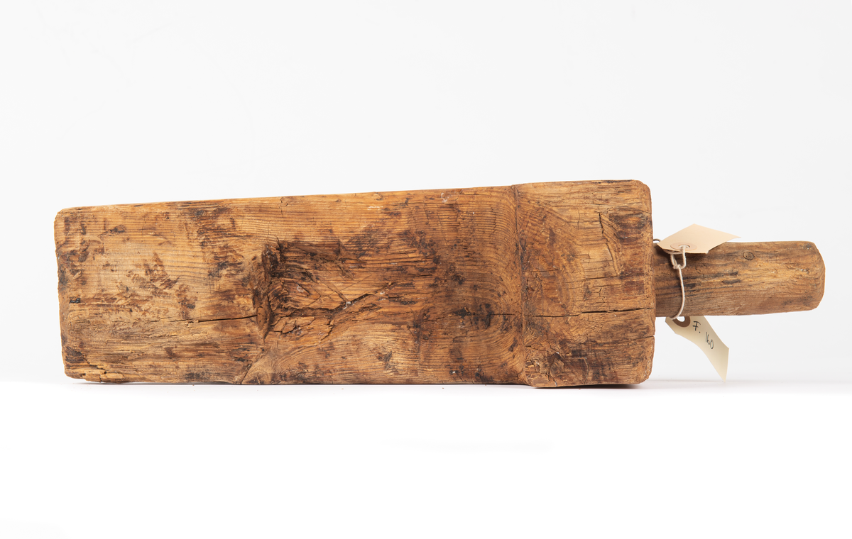 En kil med ett runt handtag som mäter 45 mm i diameter och är 105 mm långt. Ser ut som en kil.