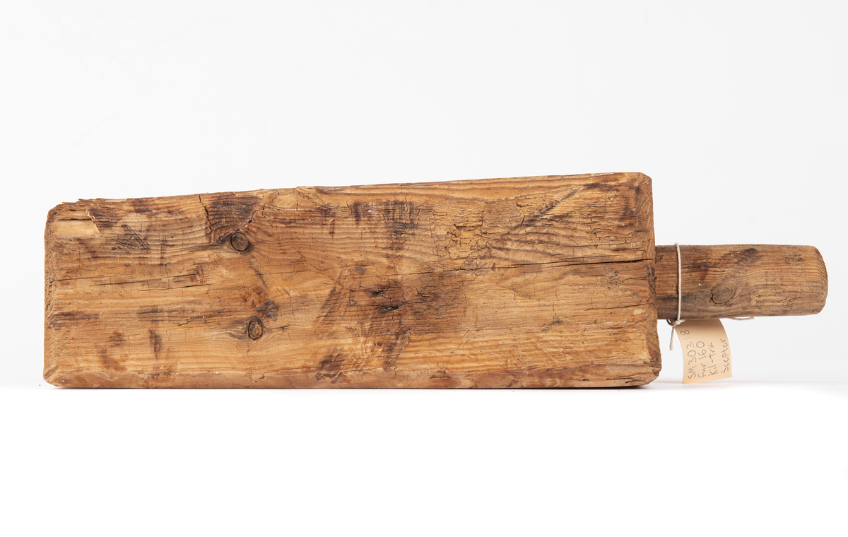 En kil med ett runt handtag som mäter 45 mm i diameter och är 105 mm långt. Ser ut som en kil.