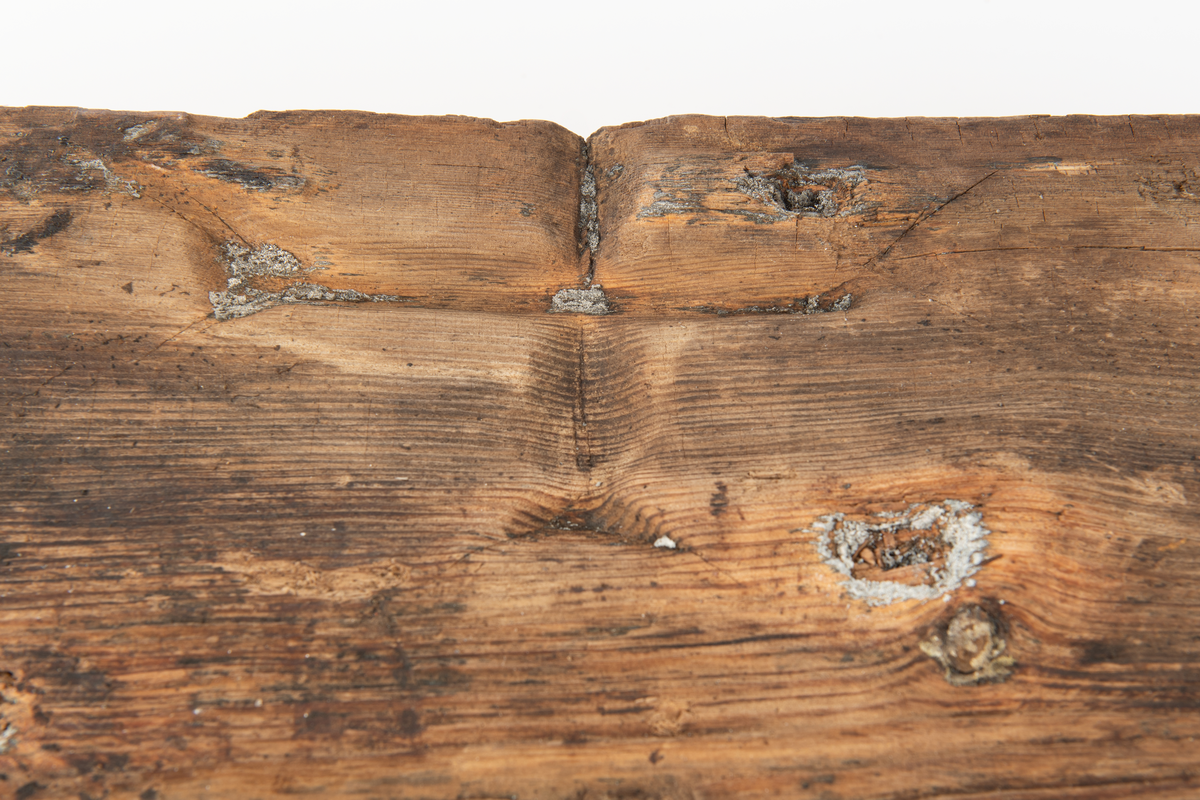 Del av fyrhydning eller extra skrov med rester av fibermatta. Möjligen rester av spik i spikhålen. Mycket järn i ytan på i synnerhet på ytan inåt med rester av fibrer.