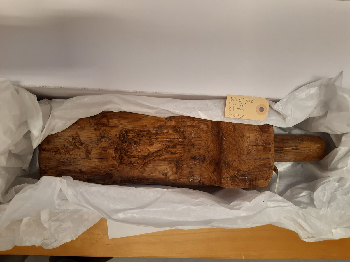 En kil med ett runt handtag som mäter 45 mm i diameter och är 105 mm långt. Ser ut som en kil.