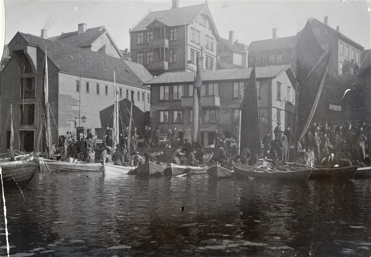 Tett med folk og småbåter ved Haugesund hav. Det er fiskere i småbåtene og tett med folk i land.