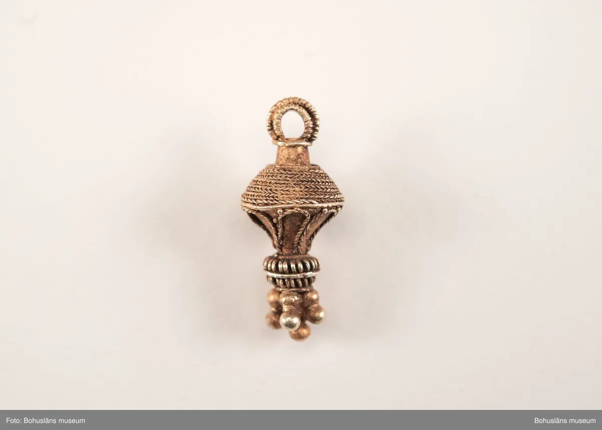 Ett utsökt intakt hängsmycke av guld, en s k päronformad berlock. Överst på hänget, finns en ögla för upphängning på ett band, halskedja eller liknande. Dekoren är utförd i s k filigranteknik, och visar på högt hantverksmässigt kunnande. Mycket tunna, tvinnade eller flätade guldtrådar är lagda ovanpå och runt hängets övre del. På hängets undre del är flera små runda guldkulor (granuleringar) fästade. Berlocken tillhör "typ III", enligt von Müllers typologi (se Müller 1958). Formmässigt har hänget sitt ursprung i östra Medelhavet och området kring Svarta havet.

Denna typ av hängsmycken är mycket ovanligt att hitta i våra trakter, det är endast en handfull som tidigare påträffats i Sverige och de flesta på Öland. Desto fler har däremot hittats i Danmark (se Rapport 2020:166, s.12).

Hänget/berlocken hittades, tillsammans med fyra spännen av brons, ett 40-tal keramikskärvor, brända och obrända ben, däribland en tand, flintavslag och bitar av en dekorerad kam av horn. Graven innehöll två individer. Den ena var jordlagd utan kremering och den andra kremerad. Den jordlagda individen hade endast ett fåtal ben och tänder bevarade. De visade sig tillhöra en ung person, ca 16-20 år gammal. Förmodligen en kvinna, vilket de gravgåvor som var nedlagda i graven visade.
Den andra individen, till vilken de brända benen hörde, var även det en ung person. 
För mer info om, och tolkning av fyndet se rapport Arkeologerna 2020:166.