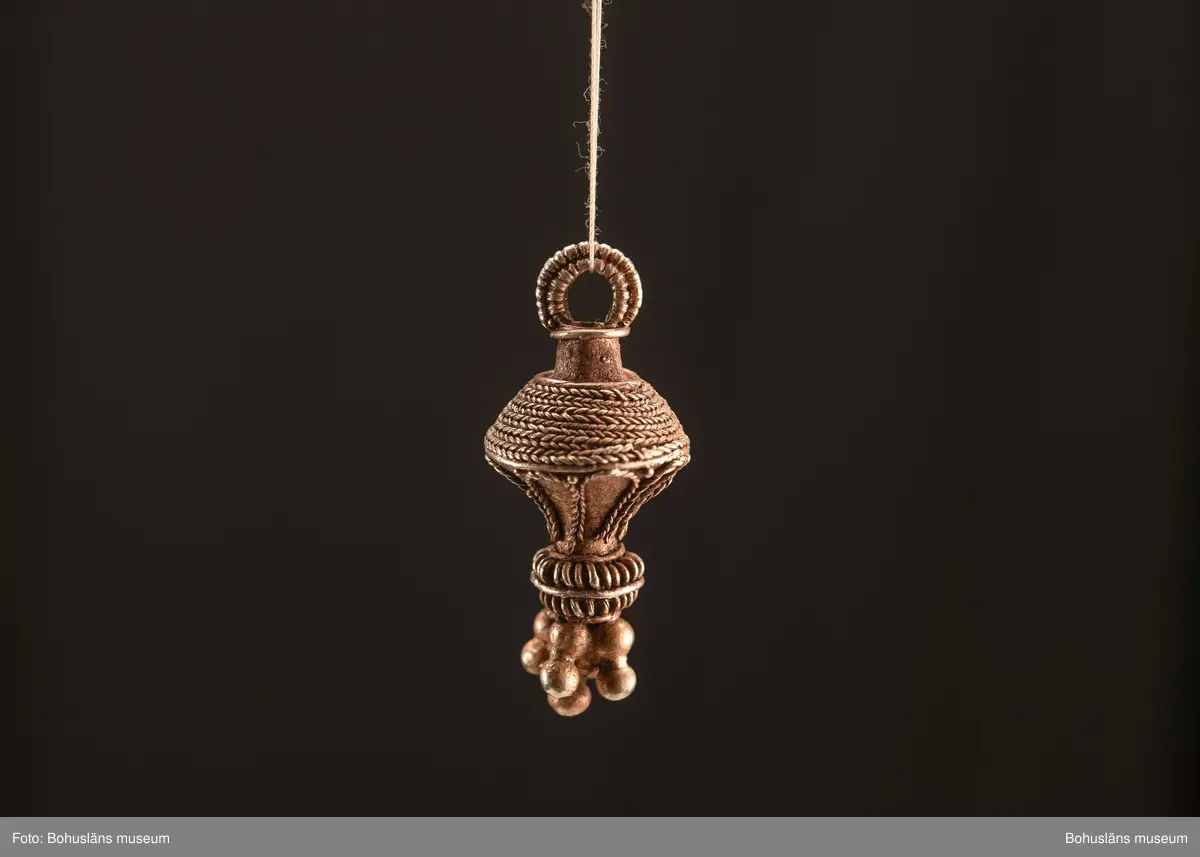 Ett utsökt intakt hängsmycke av guld, en s k päronformad berlock. Överst på hänget, finns en ögla för upphängning på ett band, halskedja eller liknande. Dekoren är utförd i s k filigranteknik, och visar på högt hantverksmässigt kunnande. Mycket tunna, tvinnade eller flätade guldtrådar är lagda ovanpå och runt hängets övre del. På hängets undre del är flera små runda guldkulor (granuleringar) fästade. Berlocken tillhör "typ III", enligt von Müllers typologi (se Müller 1958). Formmässigt har hänget sitt ursprung i östra Medelhavet och området kring Svarta havet.

Denna typ av hängsmycken är mycket ovanligt att hitta i våra trakter, det är endast en handfull som tidigare påträffats i Sverige och de flesta på Öland. Desto fler har däremot hittats i Danmark (se Rapport 2020:166, s.12).

Hänget/berlocken hittades, tillsammans med fyra spännen av brons, ett 40-tal keramikskärvor, brända och obrända ben, däribland en tand, flintavslag och bitar av en dekorerad kam av horn. Graven innehöll två individer. Den ena var jordlagd utan kremering och den andra kremerad. Den jordlagda individen hade endast ett fåtal ben och tänder bevarade. De visade sig tillhöra en ung person, ca 16-20 år gammal. Förmodligen en kvinna, vilket de gravgåvor som var nedlagda i graven visade.
Den andra individen, till vilken de brända benen hörde, var även det en ung person. 
För mer info om, och tolkning av fyndet se rapport Arkeologerna 2020:166.