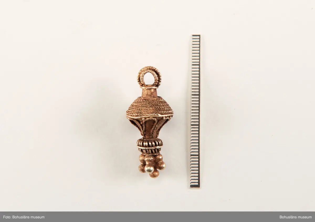 Ett utsökt intakt hängsmycke av guld, en s k päronformad berlock. Överst på hänget, finns en ögla för upphängning på ett band, halskedja eller liknande. Dekoren är utförd i s k filigranteknik, och visar på högt hantverksmässigt kunnande. Mycket tunna, tvinnade eller flätade guldtrådar är lagda ovanpå och runt hängets övre del. På hängets undre del är flera små runda guldkulor (granuleringar) fästade. Berlocken tillhör "typ III", enligt von Müllers typologi (se Müller 1958). Formmässigt har hänget sitt ursprung i östra Medelhavet och området kring Svarta havet.

Denna typ av hängsmycken är mycket ovanligt att hitta i våra trakter, det är endast en handfull som tidigare påträffats i Sverige och de flesta på Öland. Desto fler har däremot hittats i Danmark (se Rapport 2020:166, s.12).

Hänget/berlocken hittades, tillsammans med fyra spännen av brons, ett 40-tal keramikskärvor, brända och obrända ben, däribland en tand, flintavslag och bitar av en dekorerad kam av horn. Graven innehöll två individer. Den ena var jordlagd utan kremering och den andra kremerad. Den jordlagda individen hade endast ett fåtal ben och tänder bevarade. De visade sig tillhöra en ung person, ca 16-20 år gammal. Förmodligen en kvinna, vilket de gravgåvor som var nedlagda i graven visade.
Den andra individen, till vilken de brända benen hörde, var även det en ung person. 
För mer info om, och tolkning av fyndet se rapport Arkeologerna 2020:166.