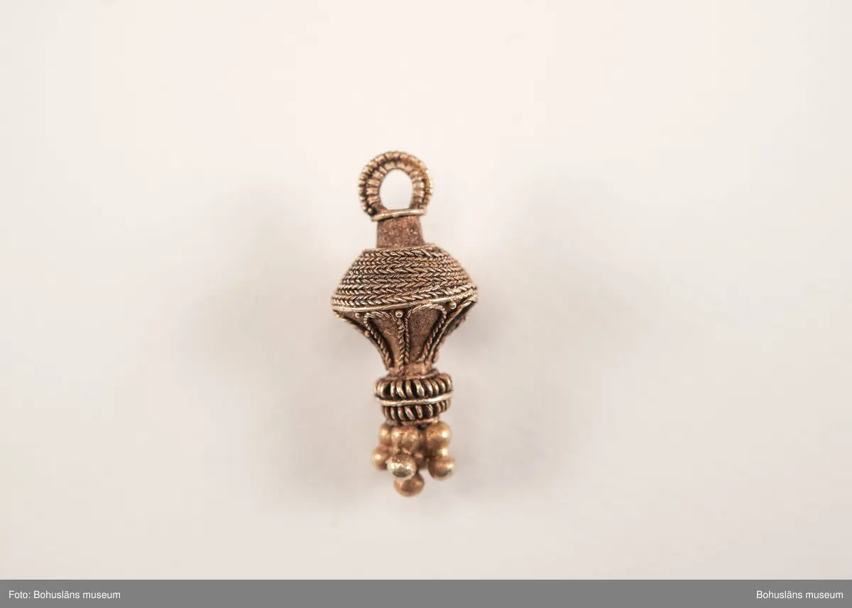 Ett utsökt intakt hängsmycke av guld, en s k päronformad berlock. Överst på hänget, finns en ögla för upphängning på ett band, halskedja eller liknande. Dekoren är utförd i s k filigranteknik, och visar på högt hantverksmässigt kunnande. Mycket tunna, tvinnade eller flätade guldtrådar är lagda ovanpå och runt hängets övre del. På hängets undre del är flera små runda guldkulor (granuleringar) fästade. Berlocken tillhör "typ III", enligt von Müllers typologi (se Müller 1958). Formmässigt har hänget sitt ursprung i östra Medelhavet och området kring Svarta havet.

Denna typ av hängsmycken är mycket ovanligt att hitta i våra trakter, det är endast en handfull som tidigare påträffats i Sverige och de flesta på Öland. Desto fler har däremot hittats i Danmark (se Rapport 2020:166, s.12).

Hänget/berlocken hittades, tillsammans med fyra spännen av brons, ett 40-tal keramikskärvor, brända och obrända ben, däribland en tand, flintavslag och bitar av en dekorerad kam av horn. Graven innehöll två individer. Den ena var jordlagd utan kremering och den andra kremerad. Den jordlagda individen hade endast ett fåtal ben och tänder bevarade. De visade sig tillhöra en ung person, ca 16-20 år gammal. Förmodligen en kvinna, vilket de gravgåvor som var nedlagda i graven visade.
Den andra individen, till vilken de brända benen hörde, var även det en ung person. 
För mer info om, och tolkning av fyndet se rapport Arkeologerna 2020:166.